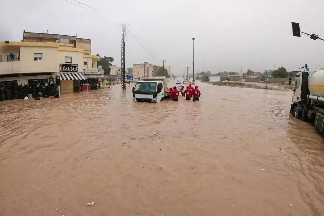 عناصر من الهلال الأحمر الليبي يحاولون تنظيف الطرق التي غمرتها الفيضانات في بلدة البيضاء، شرق ليبيا. © أ ف ب